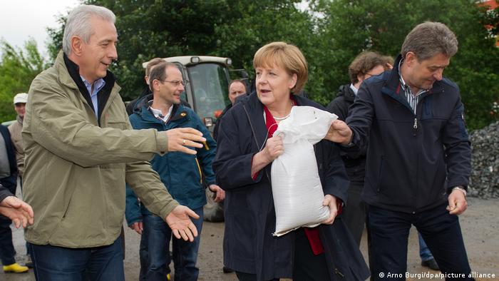 Angela Merkel passing a sandbag to then-Premier of Saxony, Stanislav Tillich