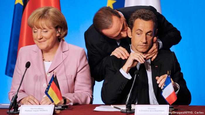 Silvio Berlusconi (center), Nicolas Sarkozy (right, with Berlusconi's hands on his shoulders) and Angela Merkel