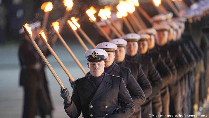 Soldiers carry torches during the military parade bidding Merkel farewell